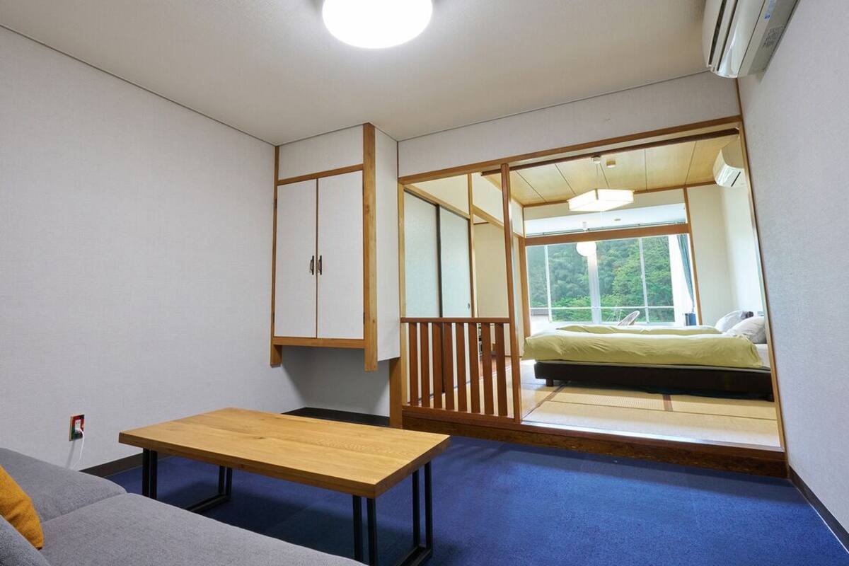 A room with a sofa, a small table, a bed with a view, and sliding doors.