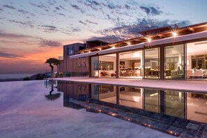 A modern house with a large glass facade, a pool, and a tree in the background. - Tropical Castle Layan by RESAVA (Choeng Thale)