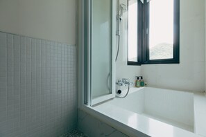 Une salle de bain avec une baignoire, une douche et une fenêtre.