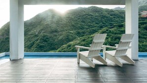 A covered outdoor area with two Adirondack chairs facing a mountainous landscape. - Adagio Jinguashi (New Taipei City)