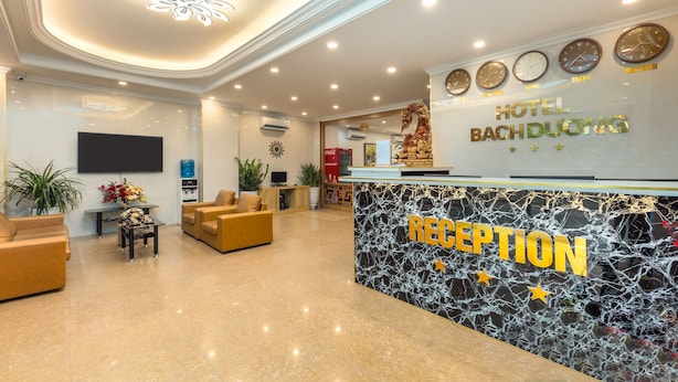 Zona de recepción de hotel con un mostrador de mármol, varios relojes y un televisor de pantalla plana.