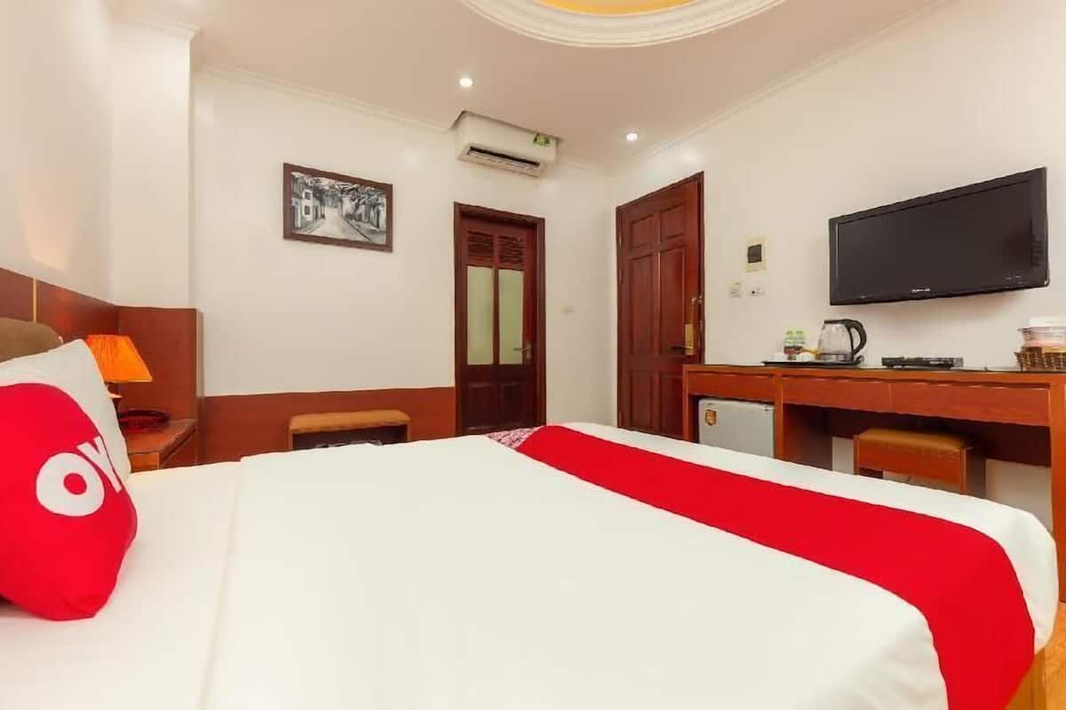 Una habitación de hotel con cama, escritorio, televisor y puerta.