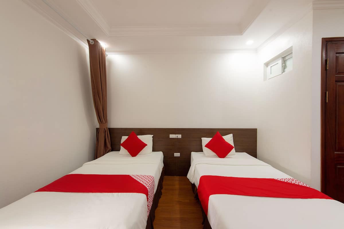 Una habitación de hotel con dos camas, cada una con una colcha roja y blanca y almohadas a juego.
