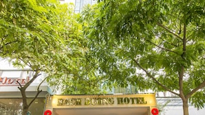 La entrada al HOTEL BACH DUONG con una escalera que lleva a la recepción, plantas en macetas y una moto estacionada afuera.