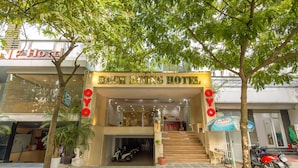 La entrada del HOTEL BACH DUONG, con una escalera que lleva a la entrada, un estacionamiento con scooters y un cartel que dice La Vie.