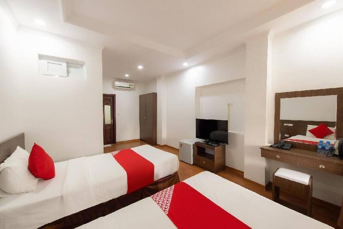Una habitación de hotel con dos camas, un escritorio, un televisor y un espejo.