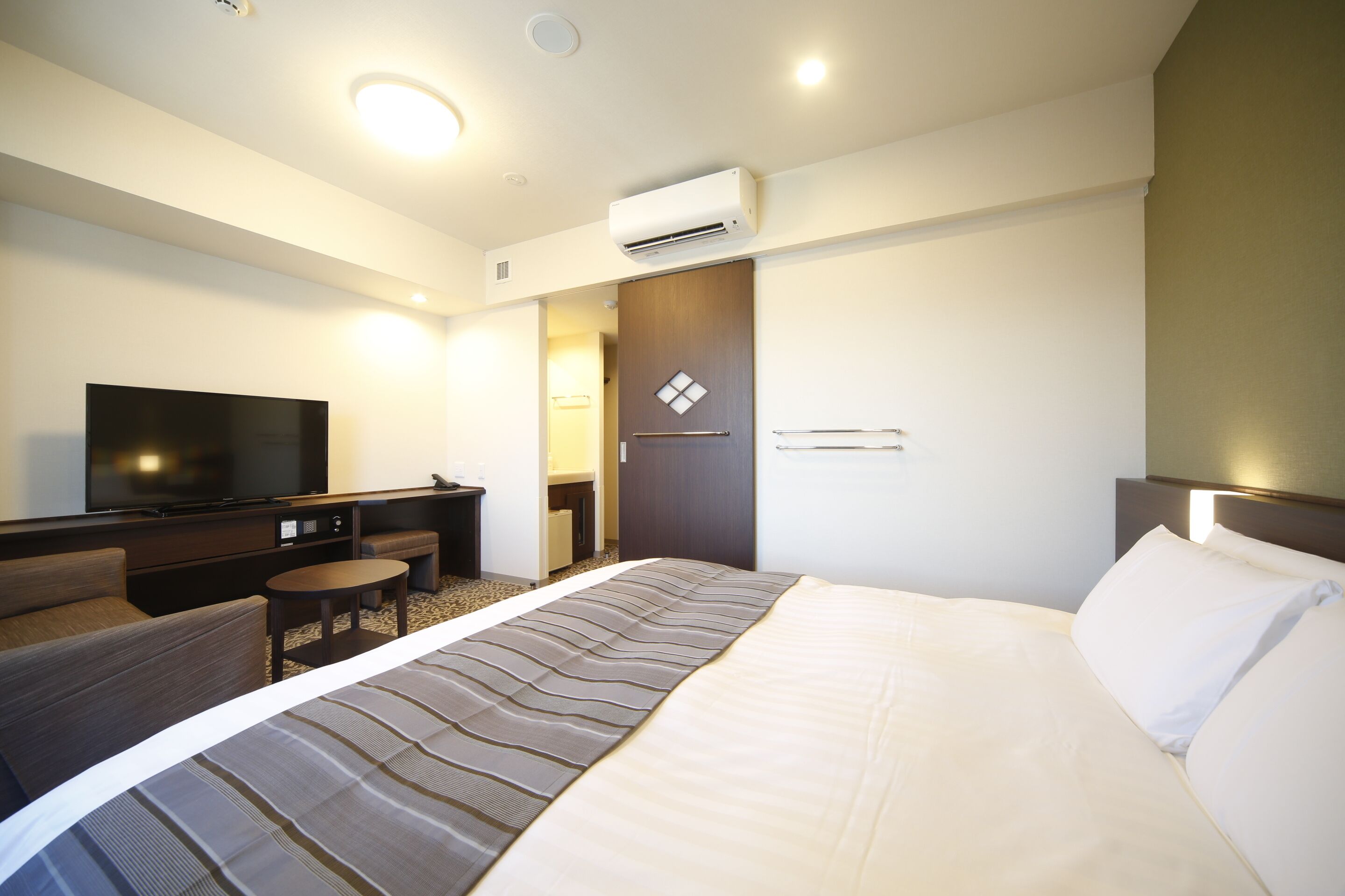 A hotel room with a bed, a TV, a desk, and a chair.