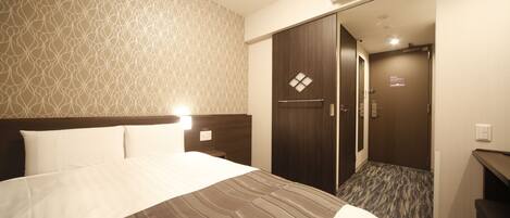 A hotel room with a bed, a desk, a wardrobe, and a bathroom.