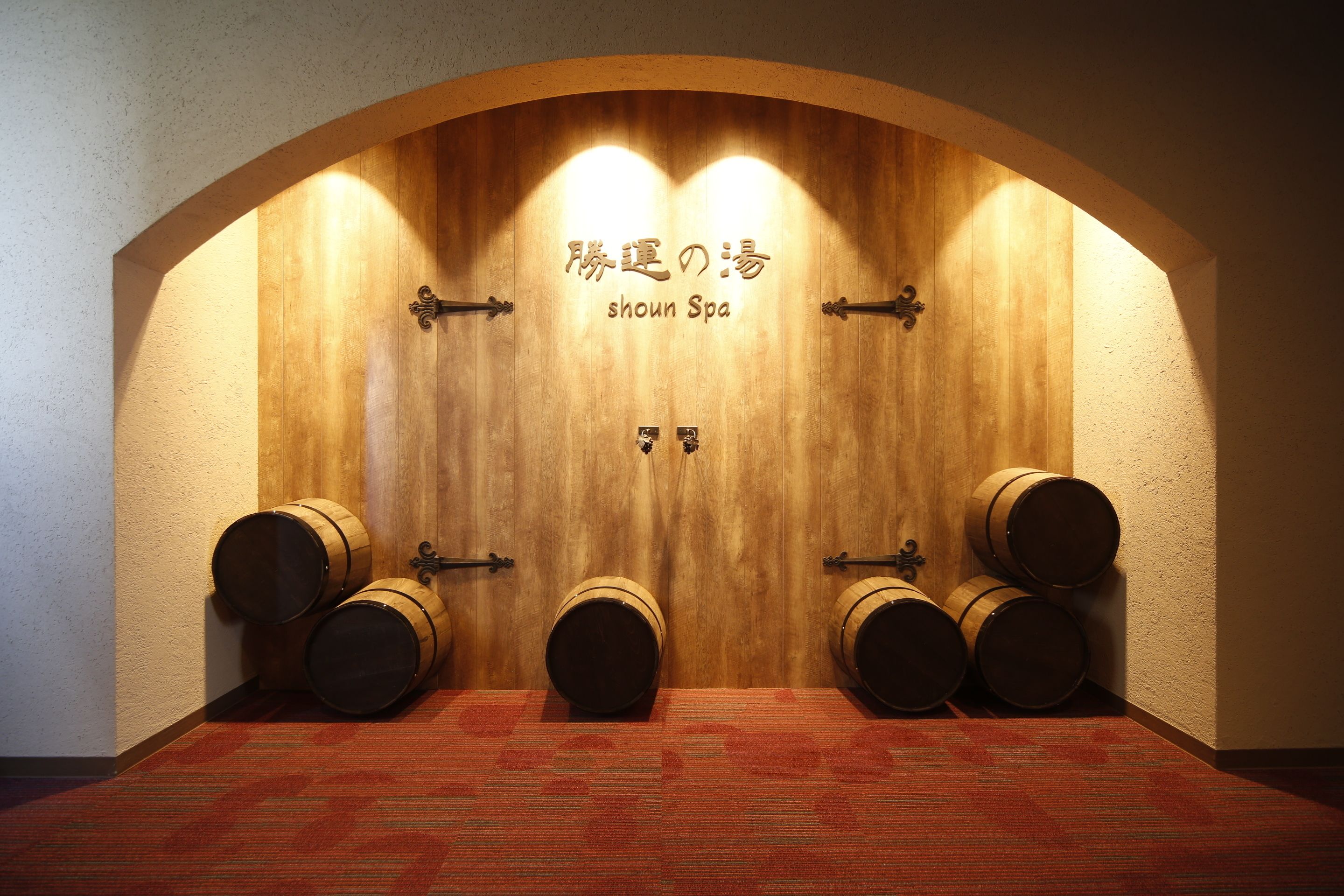 A wooden door with the text "showned Spa" and three barrels in a room with a patterned carpet.