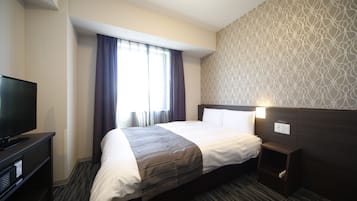 Een hotelkamer met een groot bed, een televisie, een nachtkastje en een behang met patroon.