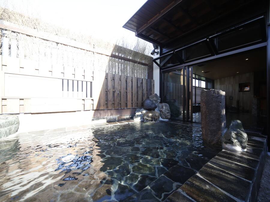 A clear outdoor pool area with stone tiles and a wooden fence.
