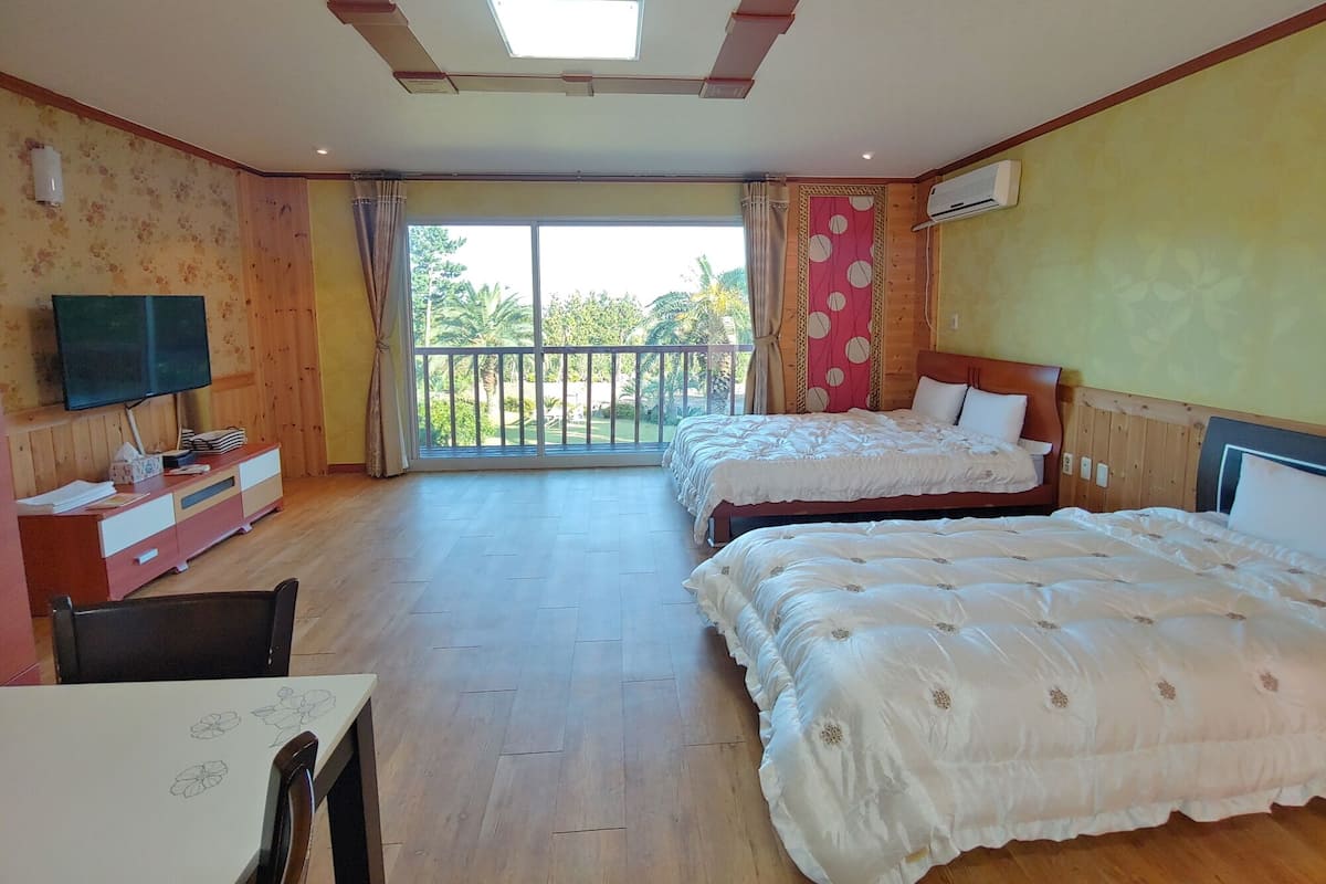 Une chambre d’hôtel avec deux lits, une télévision, un bureau et un balcon donnant sur un espace verdoyant.