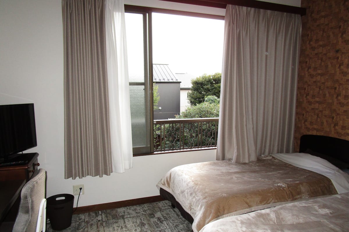 Quarto de hotel com duas camas, televisão e vista para o exterior.