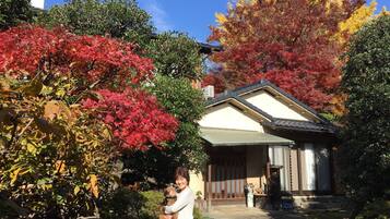 A traditional Japanese house with a covered entrance, surrounded by autumn foliage.