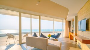 A modern living room with a large window overlooking the sea, a sofa, a coffee table, and a flat-screen TV mounted on the wall. - Seashells Hotel and Spa Phu Quoc (Phu Quoc)