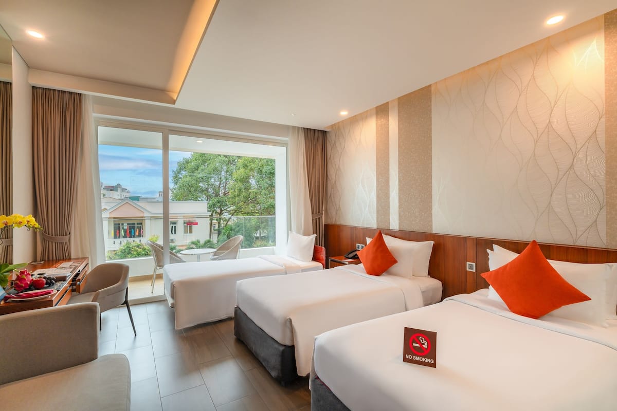 A hotel room with two beds, a desk, and a view of the outside.