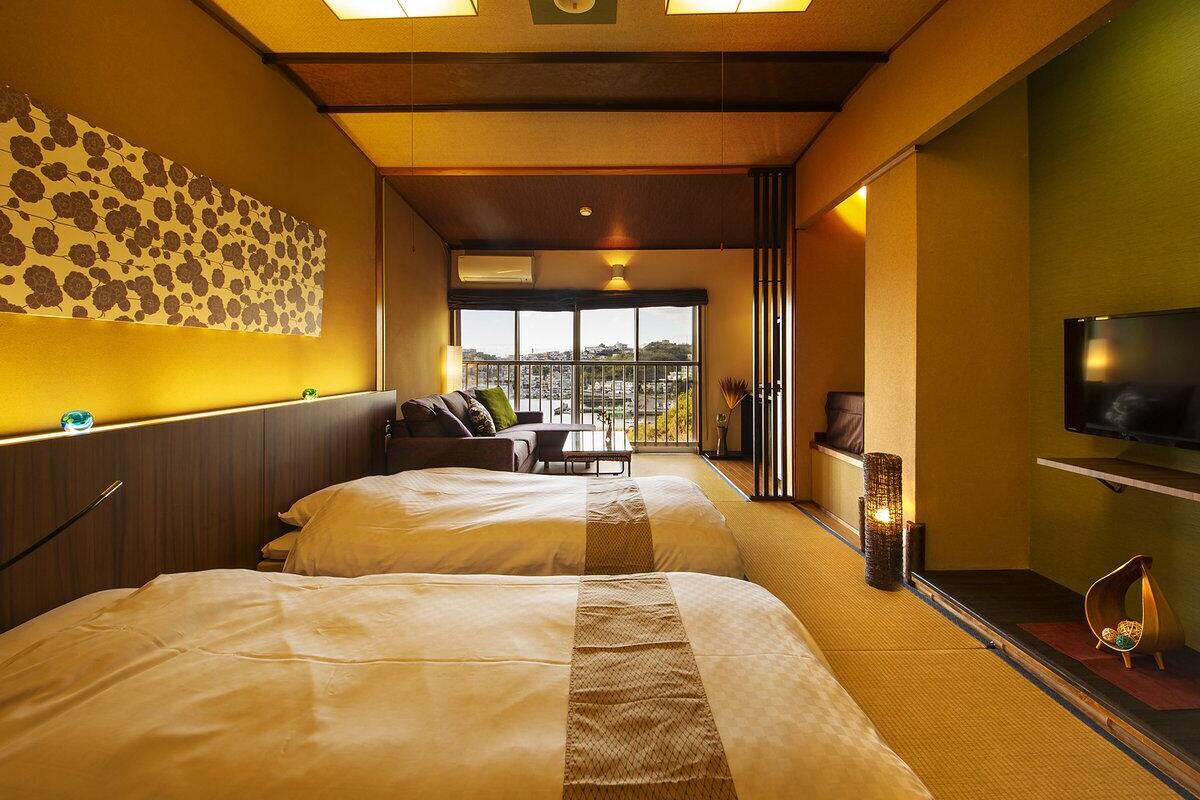 Habitación de hotel con dos camas, un sofá, un televisor y vista a la ciudad.