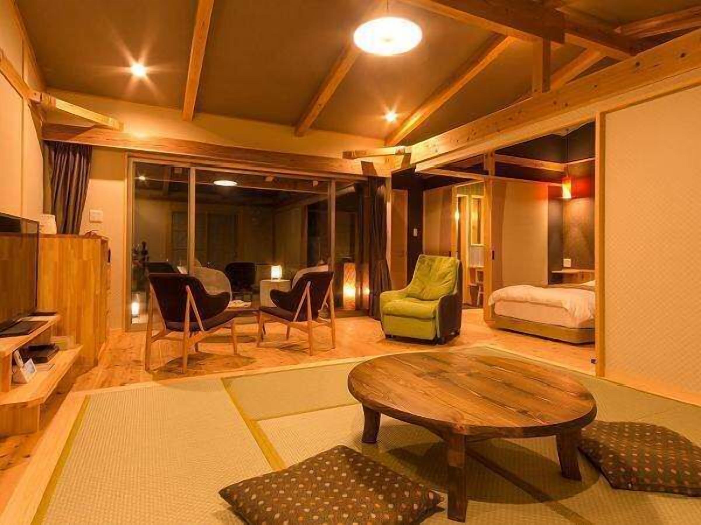 A traditional Japanese-style room with tatami flooring, a low wooden table, and a green armchair.