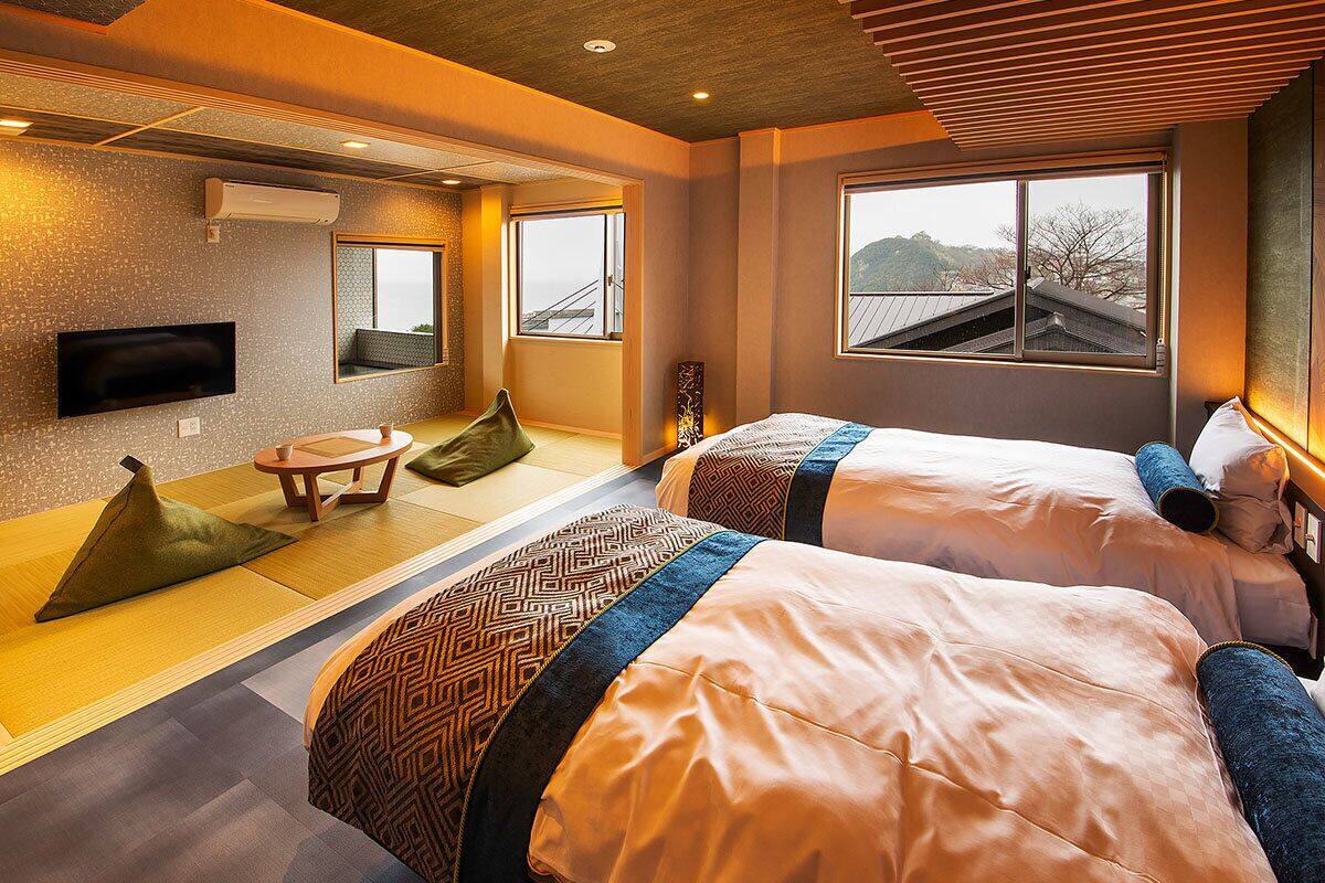 Habitación de hotel con dos camas, un televisor, una mesita y ventana con vistas.