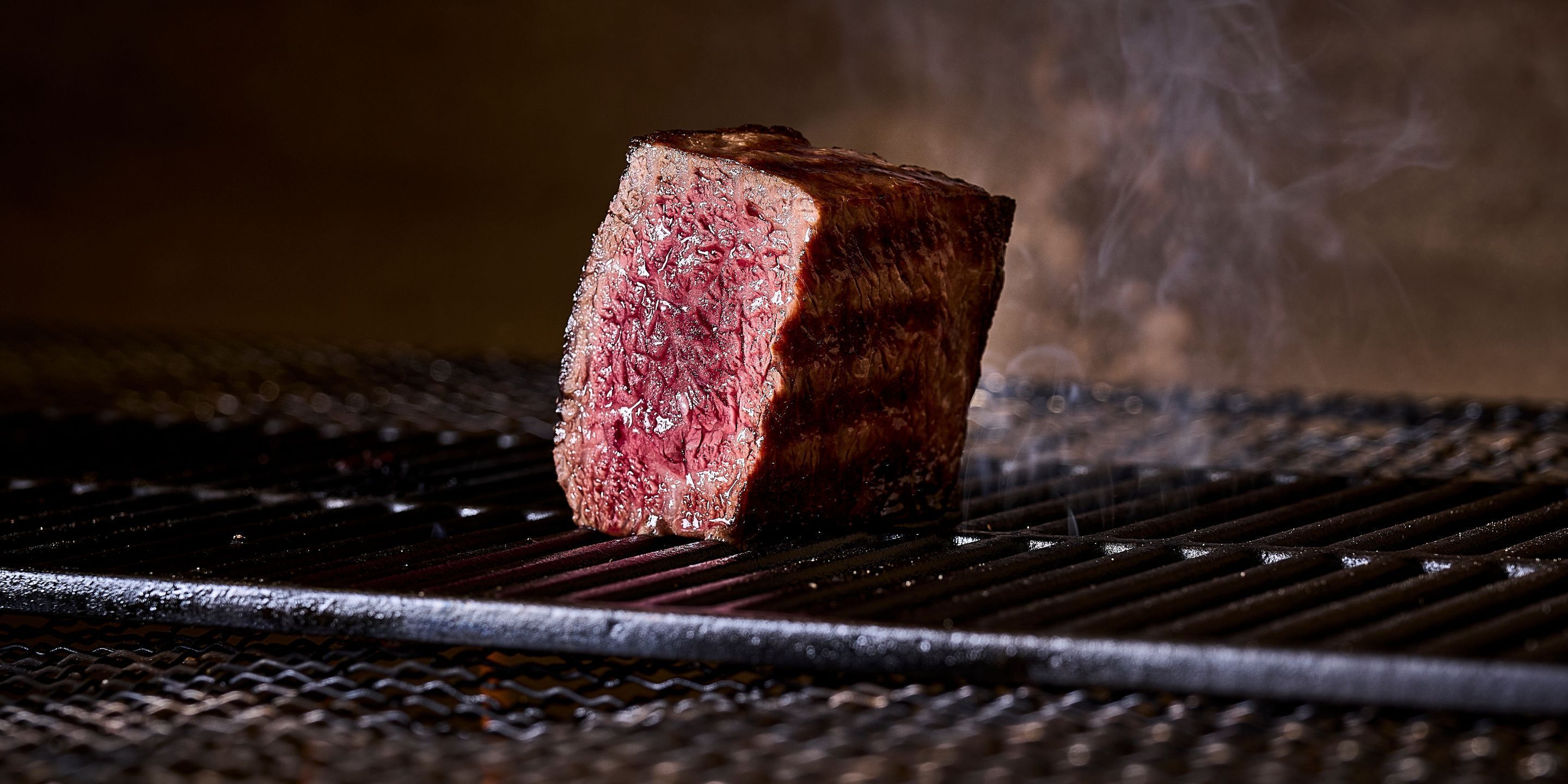Un bistec en una parrilla, con vapor saliendo.