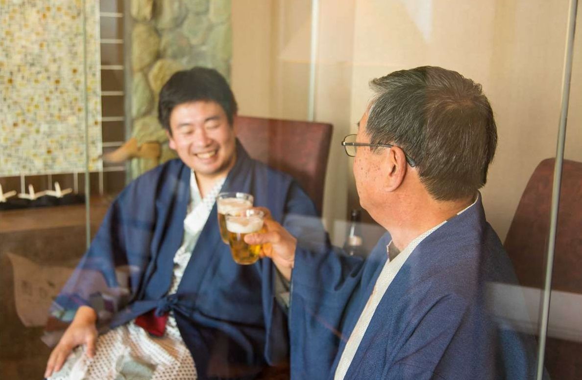 Two people in a room with a glass table, one holding a beer.
