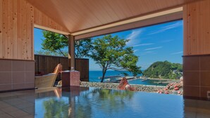 Una piscina interior moderna con vista al mar y una zona de terraza de madera.