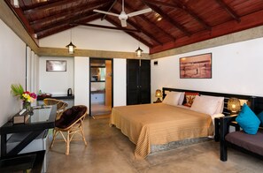 A bedroom with a bed, a desk, a chair, a nightstand, and a lamp.