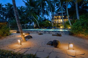Un resort con piscina, palmeras y un edificio bien iluminado.