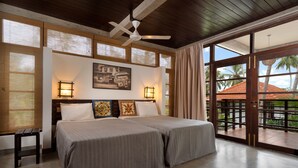 A hotel room with two beds, a ceiling fan, large windows, and a view of palm trees. - Seven Turtles Resort (Rekawa)