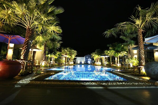 A nighttime swimming pool area with palm trees and umbrellas, surrounded by buildings. - Seava House Ao-Nang Krabi (Krabi)