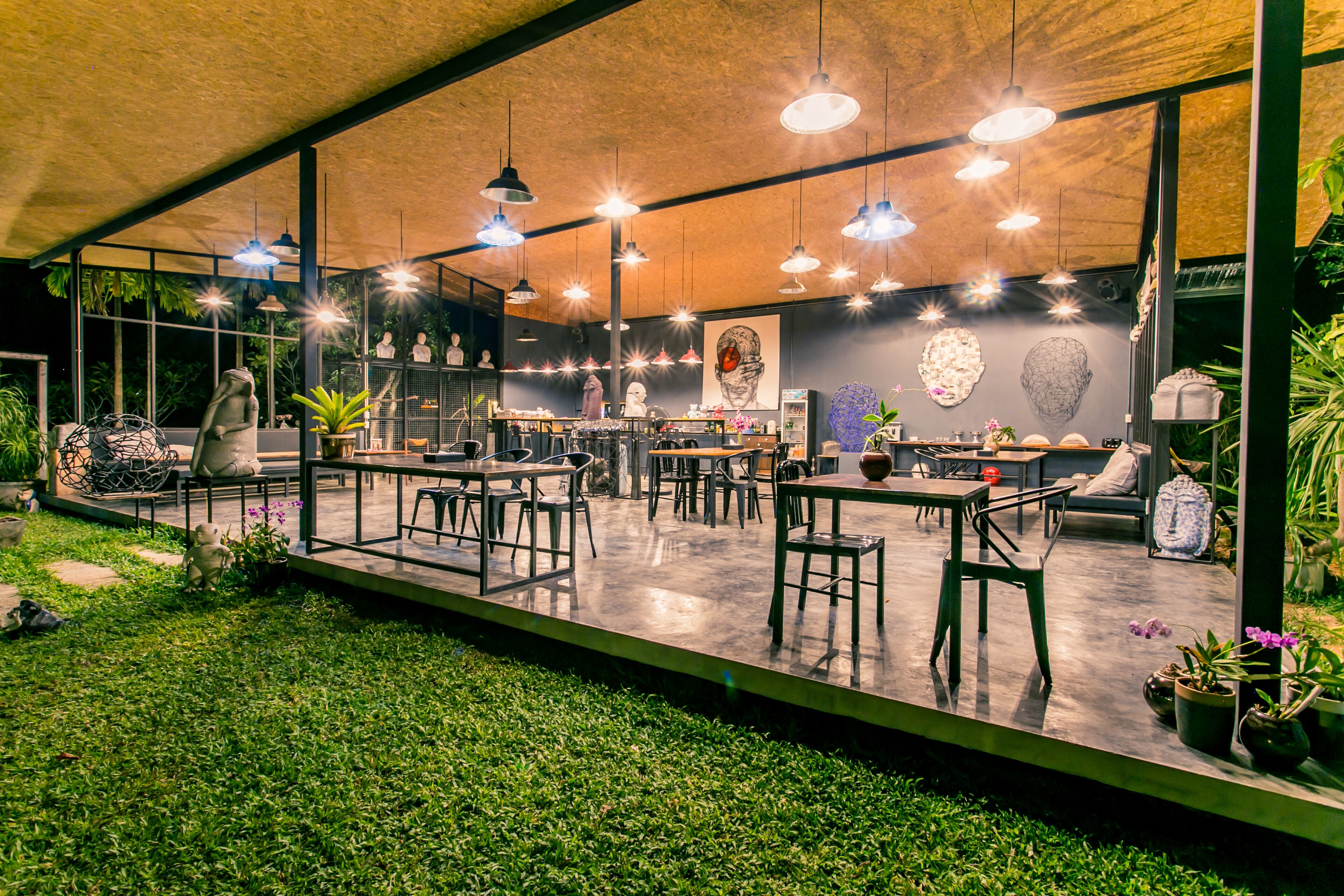 Un comedor interior con mesas y sillas, lámparas colgantes y vistas al exterior a través de amplios ventanales.