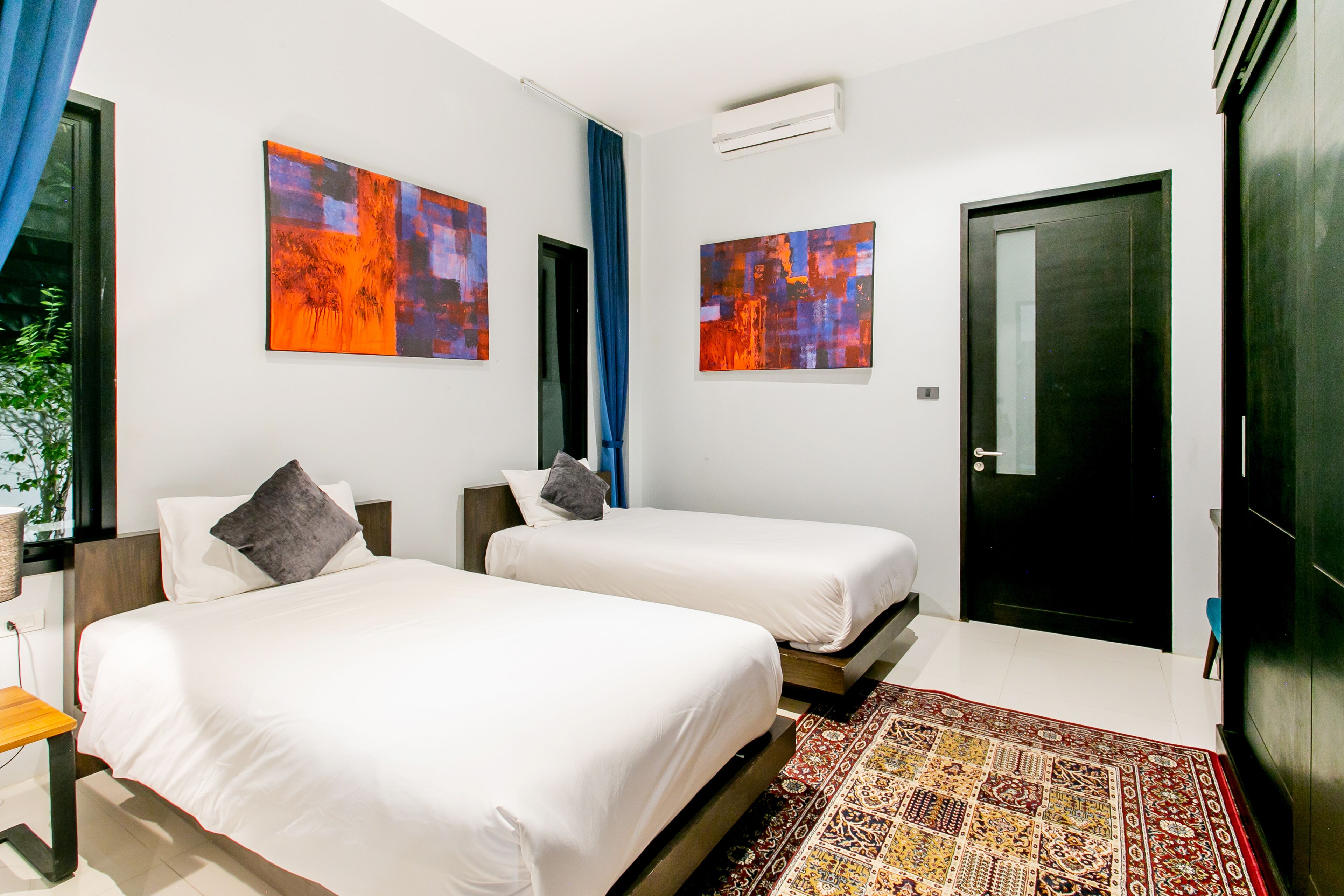Une chambre d’hôtel avec deux lits, une grande fenêtre et une porte.