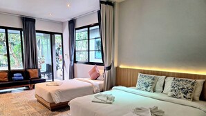 Een hotelkamer met twee bedden, een sofa en grote ramen voorzien van gordijnen.