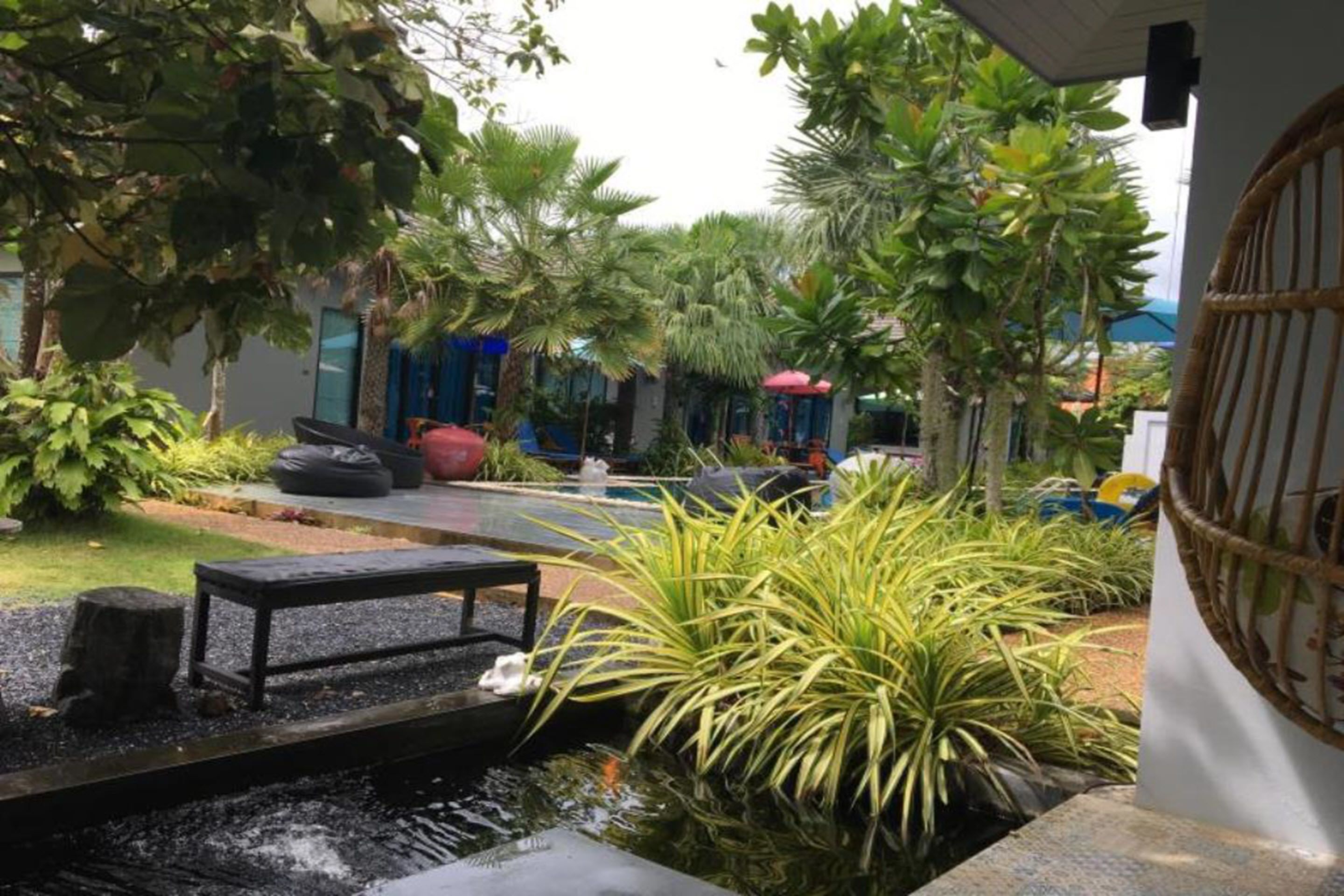 Un jardín con una pequeña fuente, asientos y diversas plantas.