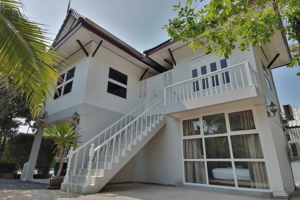 A two-story building with a balcony, a staircase, and large windows.