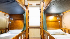 A narrow corridor with bunk beds on either side, wooden walls, and a window at the end. - Guest house Enishi - Hostel (Toyama)