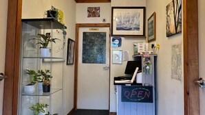 Een hal met een kroonluchter, een glazen vitrine met planten en een receptiebalie met een 'OPEN' bord.