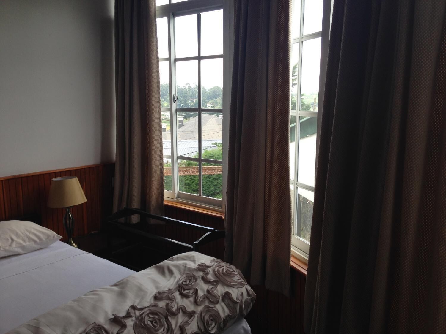 A hotel room with a bed, a desk, and a window with curtains.