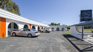 A motel with a 24-hour check-in service, a parking lot, and a building with arched windows.