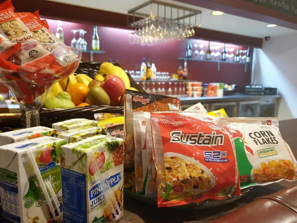 Una barra de desayuno con diversas opciones de comida, como cereales, jugo y fruta.