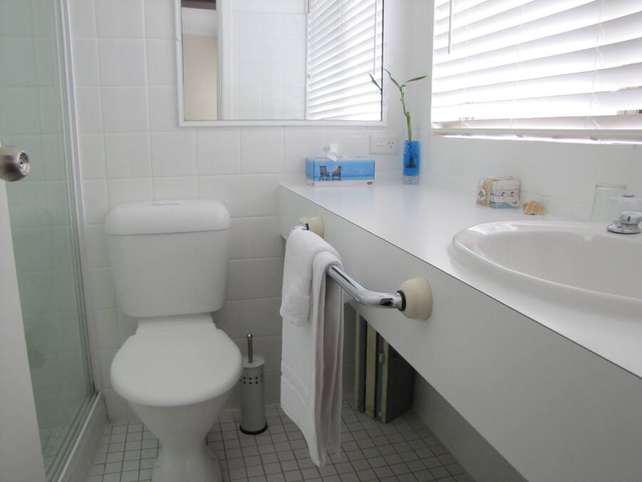 A bathroom with a toilet, sink, and mirror.