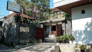 A homestay with a signboard, a stone entrance, potted plants, and a wooden staircase leading to the entrance. - Batu Kandik Homestay (Pecatu)