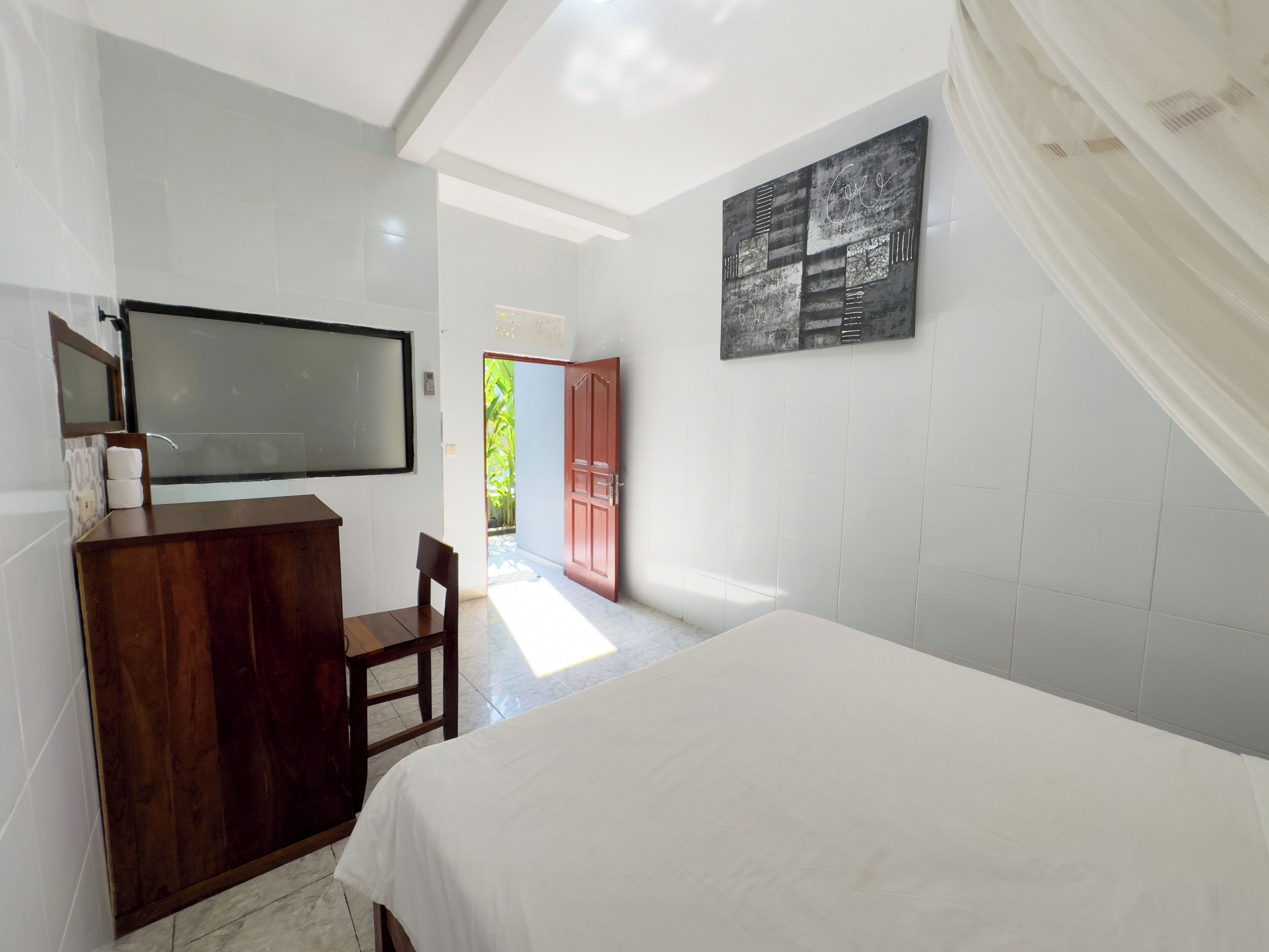A hotel room with a bed, a wooden dresser, a television, and a painting on the wall.