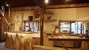 A rustic kitchen with wooden countertops, a brick backsplash, and exposed ductwork. - Guest House MAYA - Hostel (Kobe)