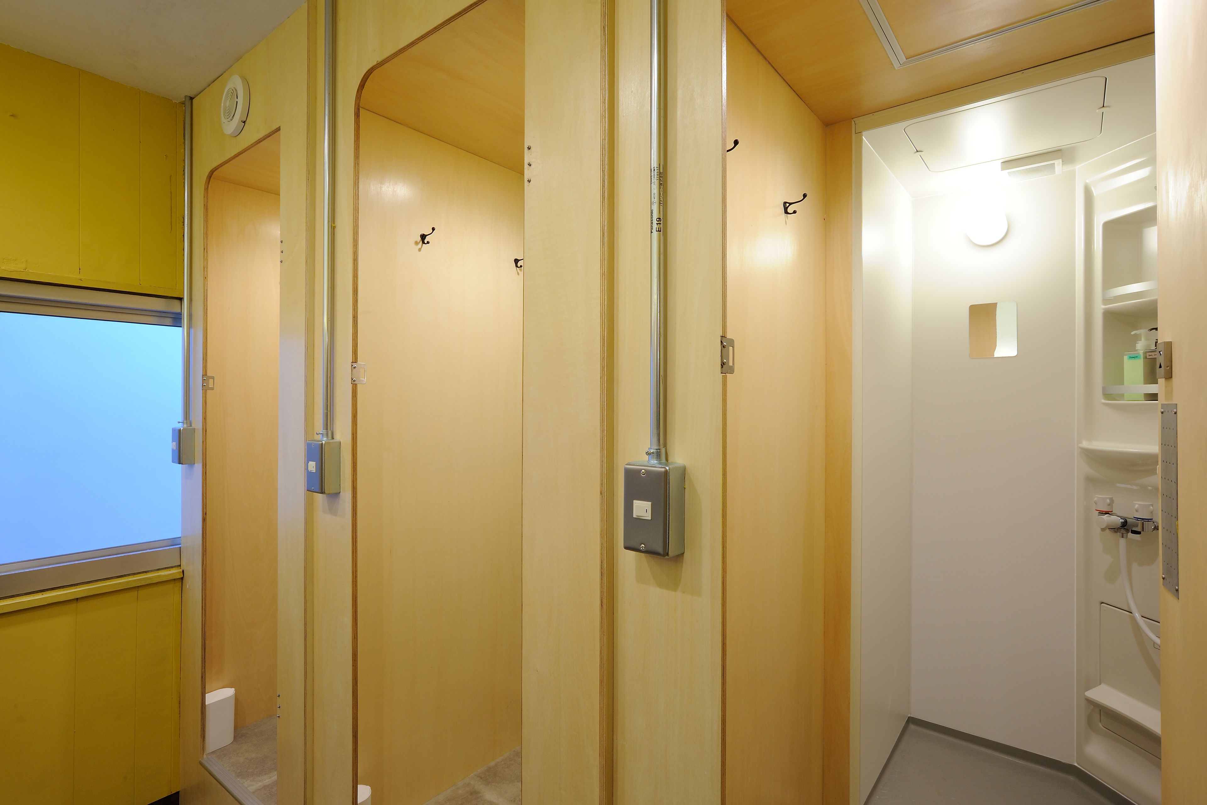 A hotel bathroom with wooden walls, a white toilet, and a shower area.