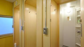 A hotel bathroom with wooden walls, a white toilet, and a shower area.