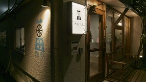 A building with a sign reading "MAYA GUEST HOUSE KOREA" and a wooden bench outside. - Guest House MAYA - Hostel (Kobe)