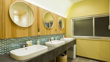 A modern bathroom with three sinks, wooden paneling, and a large mirror.