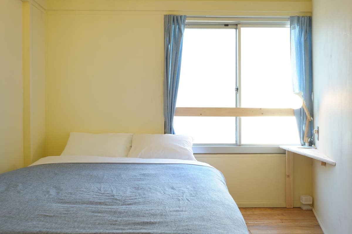 A bedroom with a bed, a window with curtains, and a radiator.