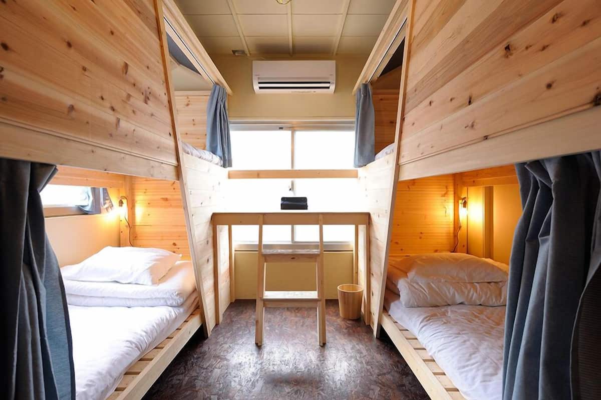 A cabin with two bunk beds, a small desk, and a window.